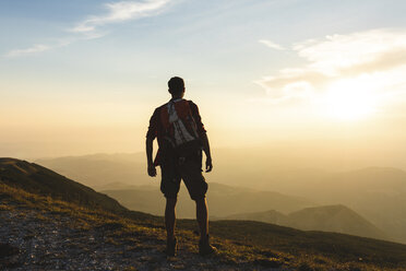 Italy, Monte Nerone, hiker on top of a mountain looking at panorama at sunset - WPEF01315