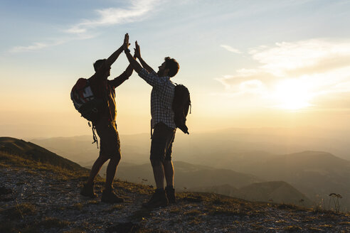 Italy, Monte Nerone, two happy and successful hikers in the mountains at sunset - WPEF01316