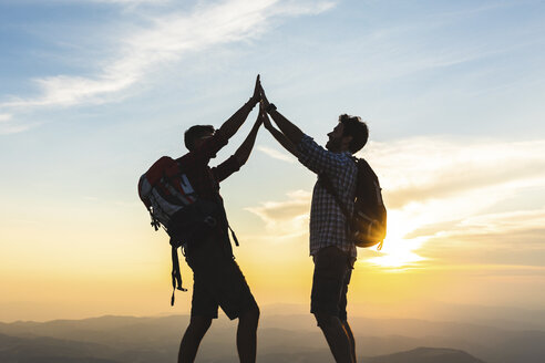 Italy, Monte Nerone, two happy and successful hikers in the mountains at sunset - WPEF01317