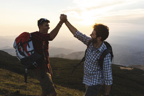 Italy, Monte Nerone, two happy and successful hikers in the mountains at sunset - WPEF01319