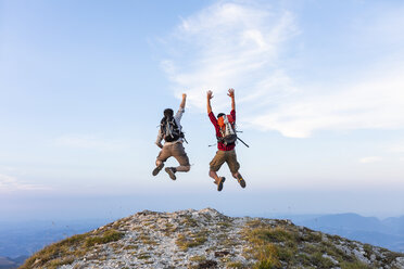 Italy, Monte Nerone, two happy and successful hikers jumping on top of a mountain - WPEF01320