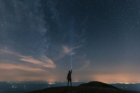 Italien, Monte Nerone, Silhouette eines Mannes mit Fackel unter Nachthimmel mit Sternen und Milchstraße - WPEF01327