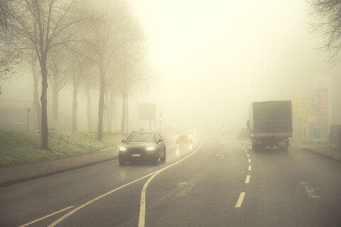 Autos fahren auf der Straße im Morgennebel, lizenzfreies Stockfoto