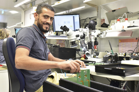 Porträt eines lächelnden Mannes, der in der Qualitätskontrolle bei der Herstellung von Leiterplatten für die Elektronikindustrie arbeitet, lizenzfreies Stockfoto