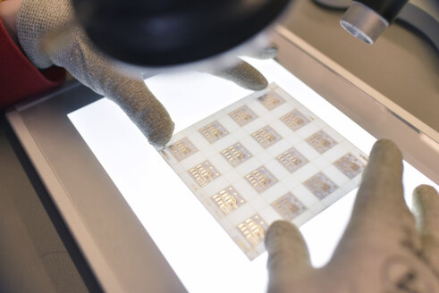 Close-up of woman working on the quality control in the manufacturing of ceramic circuit boards for the electronics industry - LYF00897