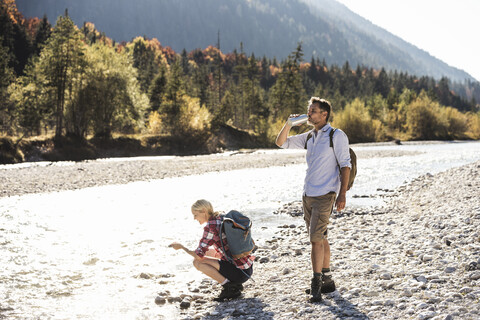 Österreich, Alpen, Wanderpärchen bei einer Pause an einem Bach, lizenzfreies Stockfoto