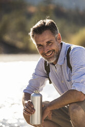 Austria, Alps, portrait of smiling man on a hiking trip having a cooling break - UUF16513