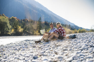 Österreich, Alpen, Wanderpärchen macht Pause an einem Bach und liest Karte - UUF16519