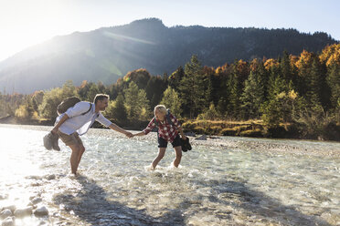 Austria, Alps, couple on a hiking trip wading in a brook - UUF16536