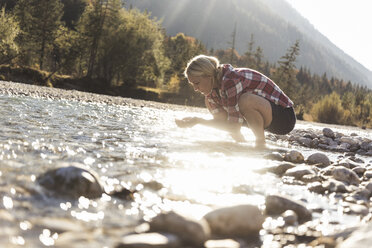 Österreich, Alpen, Frau auf Wandertour macht Pause an einem Bach - UUF16542