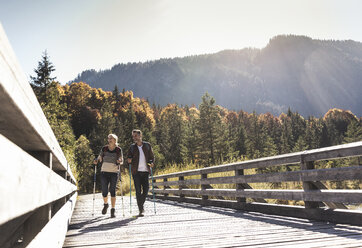 Österreich, Alpen, Paar überquert Brücke beim Wandern mit Wanderstöcken - UUF16550