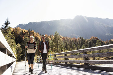 Österreich, Alpen, Paar überquert Brücke beim Wandern mit Wanderstöcken - UUF16551