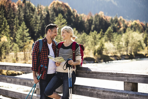 Austria, Alps, happy couple on a hiking trip with map on a bridge stock photo