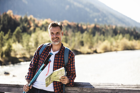 Österreich, Alpen, lächelnder Mann auf Wanderschaft mit Landkarte auf einer Brücke, lizenzfreies Stockfoto