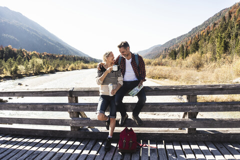 Österreich, Alpen, Wanderpärchen macht Pause auf einer Brücke, lizenzfreies Stockfoto