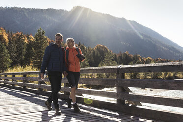 Austria, Alps, happy couple on a hiking trip crossing a bridge - UUF16580