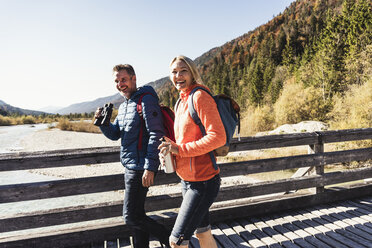 Austria, Alps, happy couple on a hiking trip crossing a bridge - UUF16583