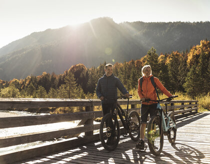Austria, Alps, couple with mountain bikes crossing a bridge - UUF16593