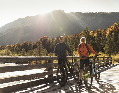 Österreich, Alpen, Paar mit Mountainbikes beim Überqueren einer Brücke - UUF16593