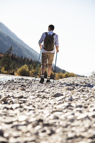 Österreich, Alpen, Mann auf Wanderschaft, der auf Kieselsteinen entlang eines Baches läuft, lizenzfreies Stockfoto