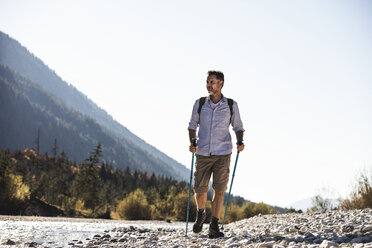 Österreich, Alpen, Mann auf Wanderschaft, der auf Kieselsteinen entlang eines Baches läuft - UUF16601