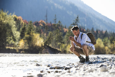 Austria, Alps, man on a hiking trip having a cooling break at a brook - UUF16605