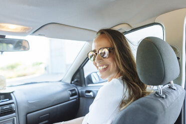 Happy woman on passenger seat in car - KIJF02226