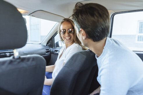 Glückliches Paar im Auto mit Mann auf Rücksitz und Frau auf Beifahrersitz - KIJF02227