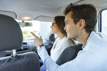 Couple in car with woman on front passenger seat and man pointing his finger from the back seat - KIJF02228