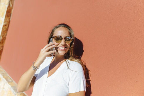 Lächelnde Frau am Mobiltelefon an einem sonnigen Tag - KIJF02251