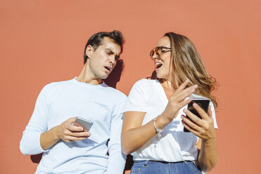 Couple with cell phones outdoors on a sunny day - KIJF02252