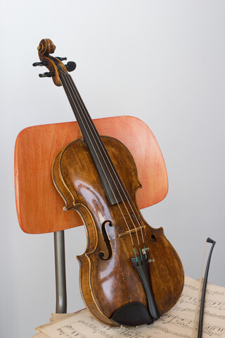 Geige, Bogen und Noten auf Holzstuhl, Nahaufnahme, lizenzfreies Stockfoto