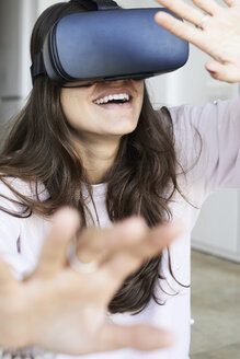Junge Frau hat Spaß mit Virtual-Reality-Headsets zu Hause - IGGF00740