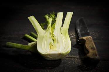 Fenchel in Scheiben geschnitten und Küchenmesser auf dunklem Holz - MAEF12773