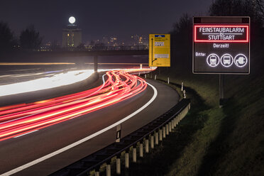 Germany, Stuttgart, Warning sign for particulate pollution alert and traffic at night - WDF05049