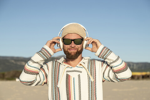 Mann mit Kopfhörern und Sonnenbrille am Strand, lizenzfreies Stockfoto