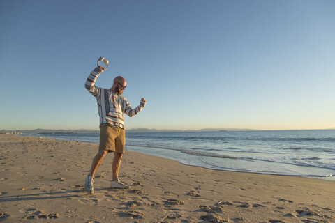 Mann mit Kopfhörern und Sonnenbrille am Strand, lizenzfreies Stockfoto