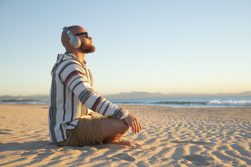 Man with headphones sitting at the beach - KBF00470