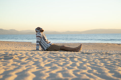 Man with headphones sitting at the beach - KBF00472