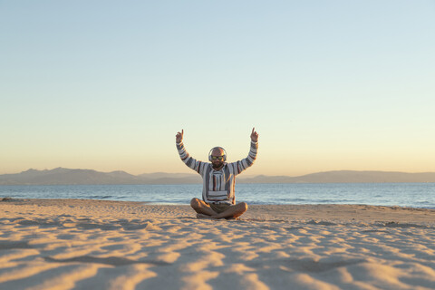 Mann mit Kopfhörern und Sonnenbrille am Strand sitzend, lizenzfreies Stockfoto