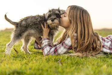 Girl lying on a meadow kissing her dog - ERRF00687