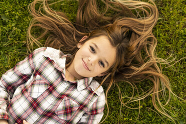 Porträt eines lächelnden Mädchens mit langen Haaren, das auf einer Wiese liegt - ERRF00688