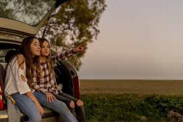 Two sisters sitting at opened tail watching sunset together - ERRF00709