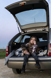 Porträt eines Mädchens, das mit seinem Hund in einem geöffneten Kofferraum sitzt - ERRF00715