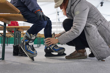 Mother helping her son to put on ice skates - ZEDF01827