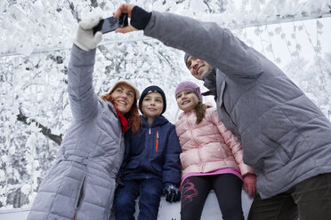 Familie mit zwei Kindern auf der Eisbahn, die Selfies mit ihrem Smartphone machen - ZEDF01832