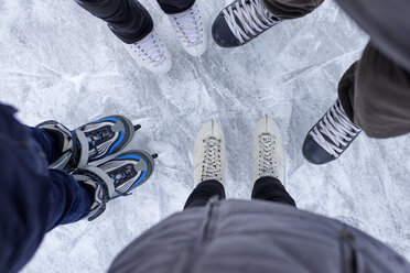 Family with two kids standing on the ice rink, close up of shoes - ZEDF01837
