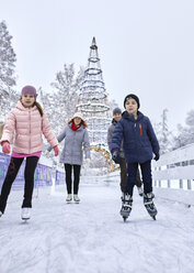 Familie mit zwei Kindern beim Schlittschuhlaufen auf der Eislaufbahn - ZEDF01839