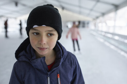 Porträt eines Jungen mit Wollmütze, der sich beim Schlittschuhlaufen auf der Eisbahn amüsiert - ZEDF01847
