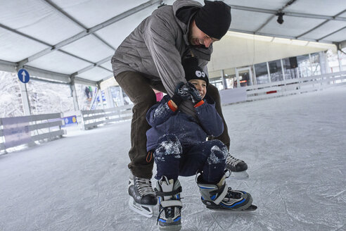 Vater und Sohn laufen gemeinsam Schlittschuh und haben Spaß auf der Eisbahn - ZEDF01858